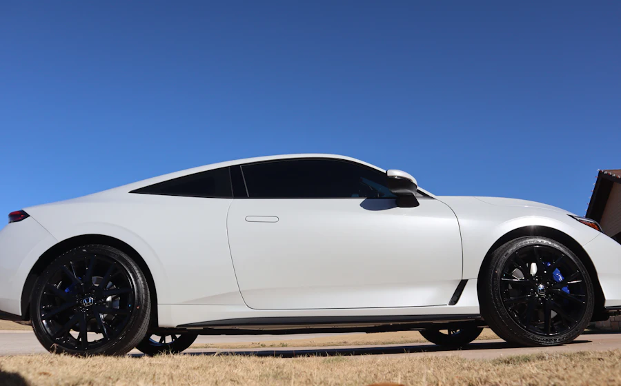 Carro branco com vidros escuros sob sol forte e céu azul